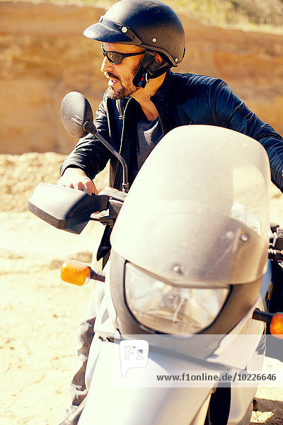 Mature man with motor bike in sand pit