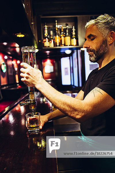 Kellner gießt Whiskey in einen irischen Pub