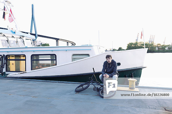 Germany  Hamburg  teenage boy with bmx bike sitting on a jetty