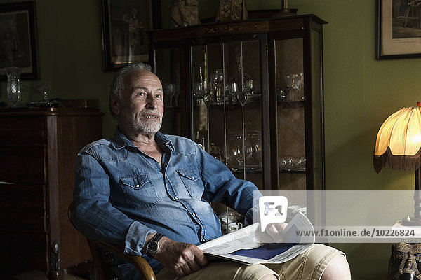 Senior man with newspaper relaxing at home