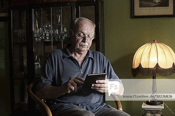 Senior Mann mit Mini-Tablette zu Hause