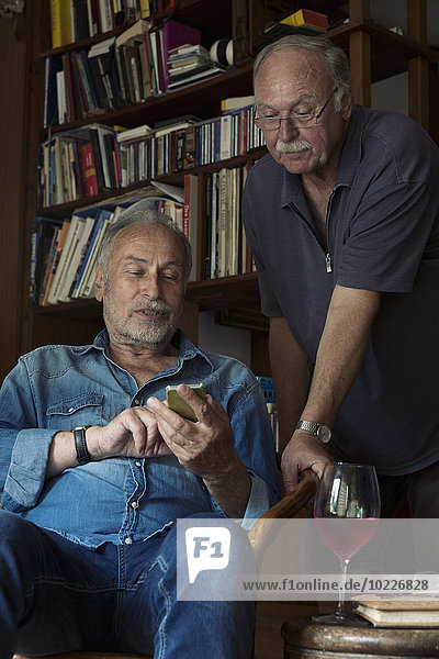 Zwei ältere Männer mit Smartphone zu Hause