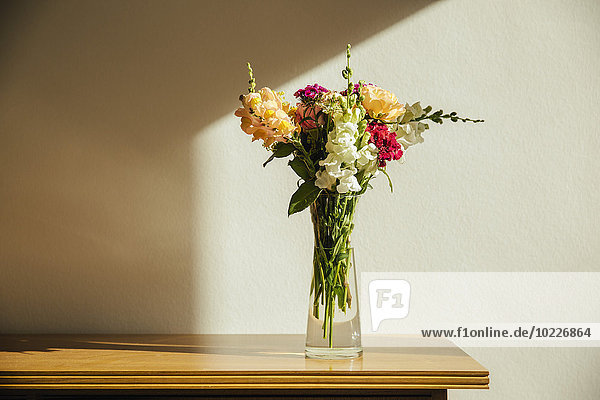 Small bouquet of summer flowers on old wooden sideboard
