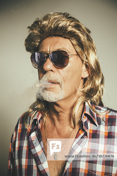 Portrait of smoking man wearing sunglasses and blond wig