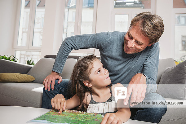 Vater und kleine Tochter mit Karte im Wohnzimmer