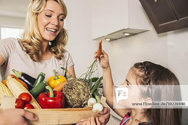 Frau und kleines Mädchen mit Holzkiste mit Gemüse