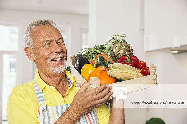 Portrait of man holding wooden box of vegetables