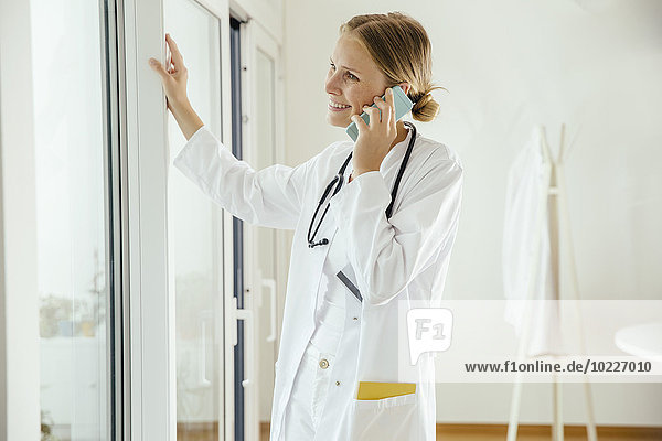 Smiling female doctor talking on cell phone
