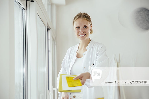 Portrait of smiling female doctor handing over medical documents
