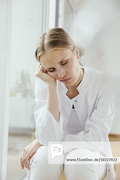 Exhausted female doctor sitting with eyes closed