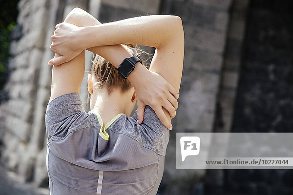 Young sporty woman with smart watch stretching