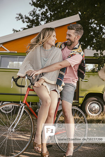 Glückliches Paar auf dem Fahrrad vor dem Van in der Natur