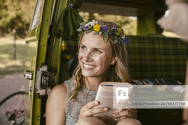 Hippie-Frau  die aus einem Buch im Van aufschaut