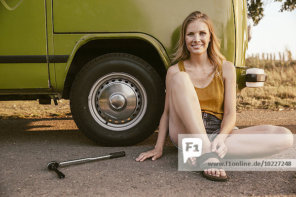 Lächelnde Frau sitzt neben einem Drehmomentschlüssel am Transporter