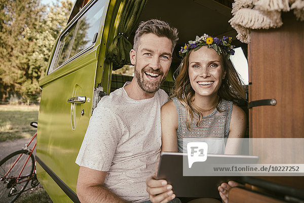Glückliches Paar mit Tablet-Computer im Lieferwagen