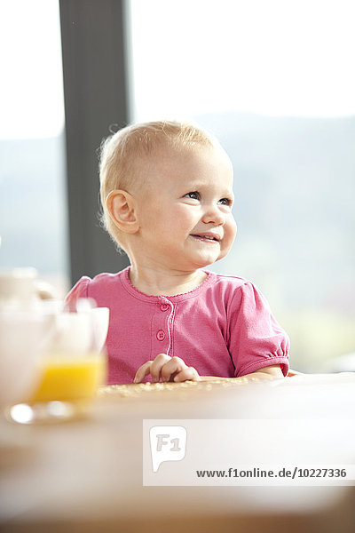 Lächelndes Baby am Frühstückstisch