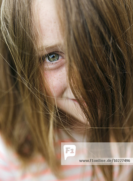 Porträt eines lächelnden Mädchens  das durch die Haare guckt.