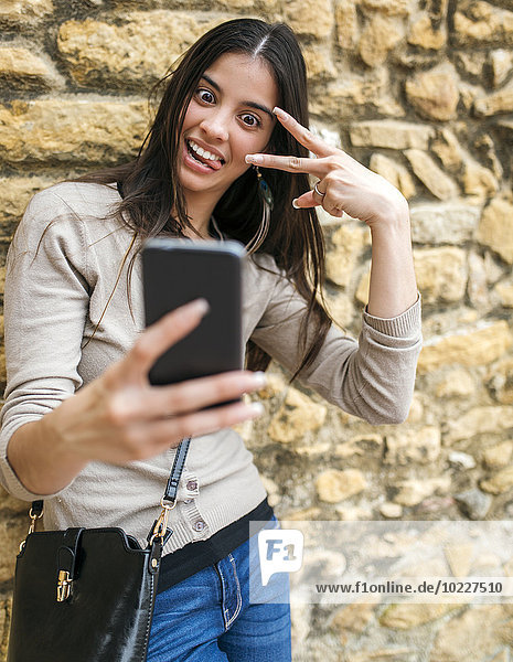 Junge Frau  die einen Selfie mit ihrem Smartphone nimmt