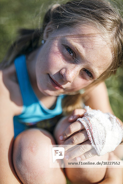 Porträt eines blonden Mädchens mit Mullbinde an der Hand