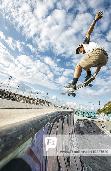 Junge Skateboarder springen in der Luft in einem Skatepark
