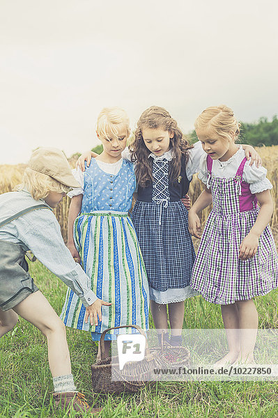 Deutschland  Sachsen  drei kleine Mädchen auf der Suche nach einem Jungen  der nach einem Korb mit Früchten greift.
