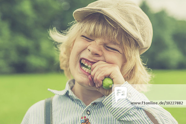 Porträt eines kleinen Jungen mit Mütze  der Gurke isst