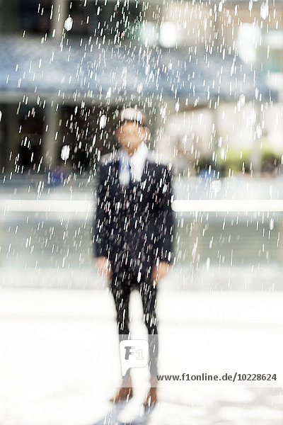 Portrait of blurred businessman standing behind a fountain