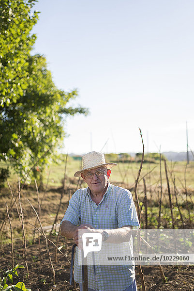Porträt eines Bauern mit Strohhut vor seinen Feldern