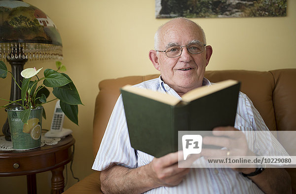 Porträt eines älteren Mannes mit Buch zu Hause