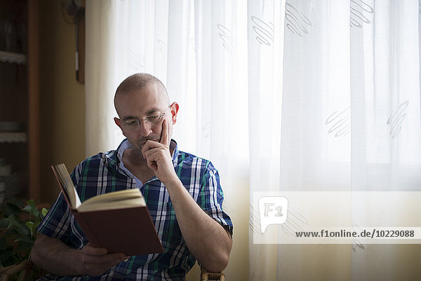 Portrait of man reading a book at home