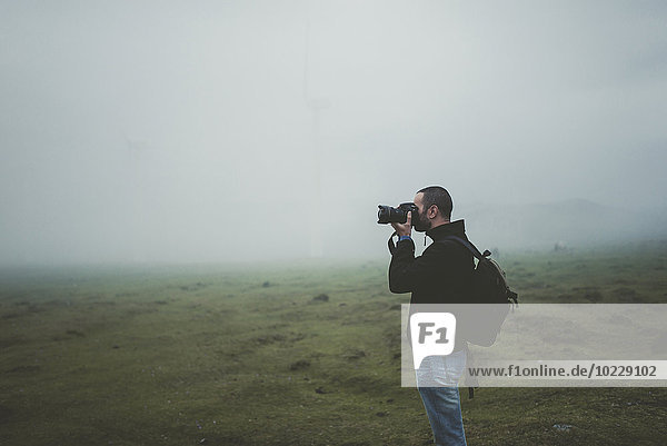 Spain  Ortigueira  photographer taking pictures on a meadow with fog