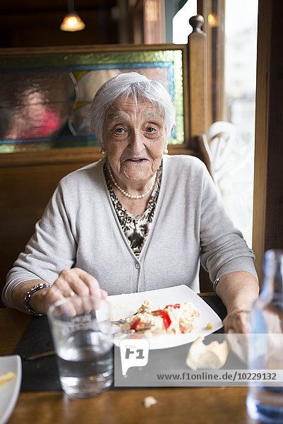 Porträt einer älteren Frau beim Essen in einem Restaurant
