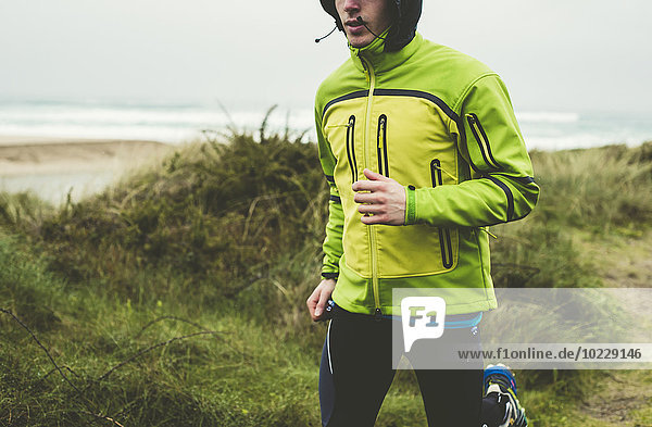 Spanien  Valdovino  junger Mann beim Joggen am Strand am Regentag