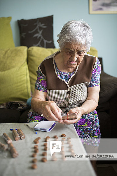 Seniorin sitzt zu Hause auf der Couch und zählt Euro-Cent-Münzen.
