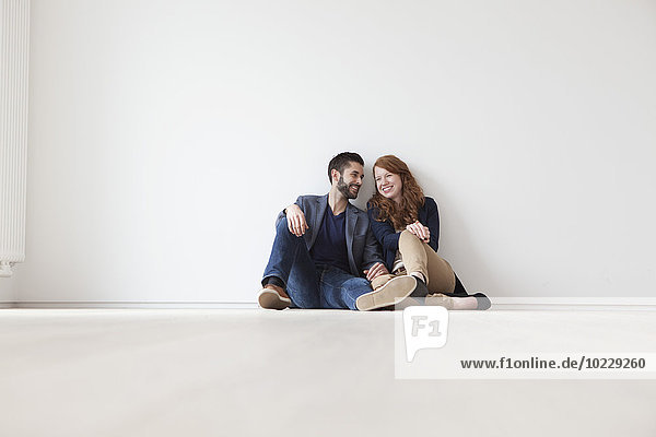 Junges Paar auf dem Boden der neuen Wohnung sitzend