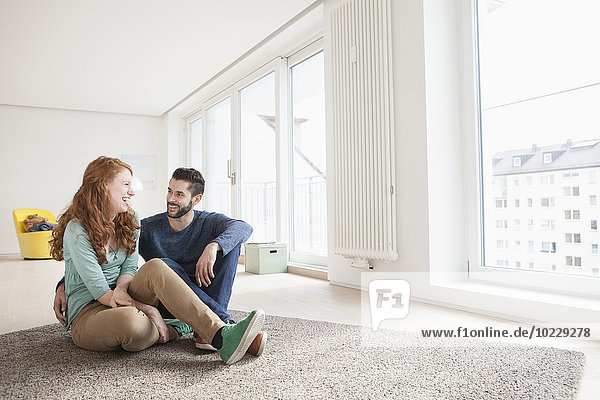 Young couple sitting on the floor of living room