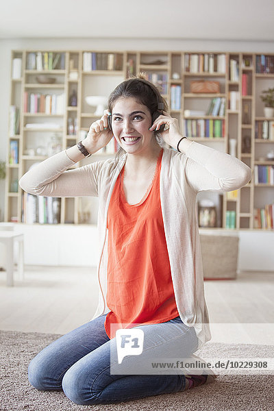 Junge Frau hört Musik mit Kopfhörern zu Hause