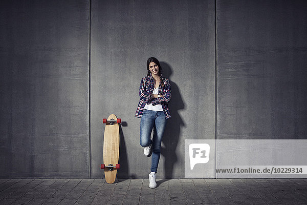 Junge Frau steht neben ihrem Longboard