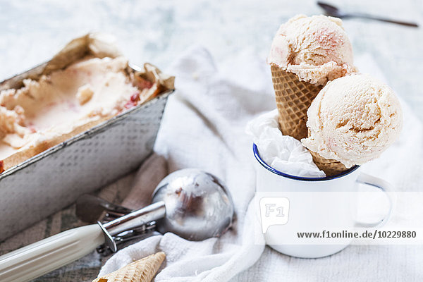 Vanilleeis mit Fruchtwirbel in der Laibpfanne  Emaillebecher mit Eistüte und Eiskugeln  Eiskugelschaufel