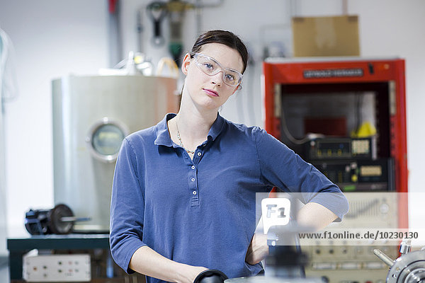 Portrait of young woman with safety goggles in workshop