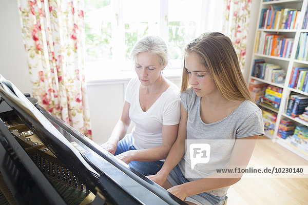 Mutter und Tochter spielen zusammen Klavier