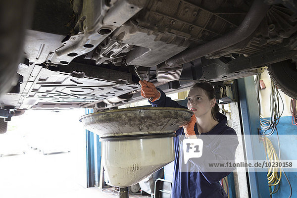 Junge Frau in Reparaturwerkstatt  Ölwechsel