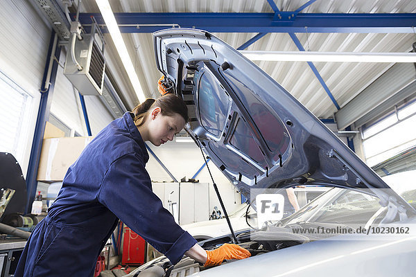 Young woman working in repair garage  checking engine
