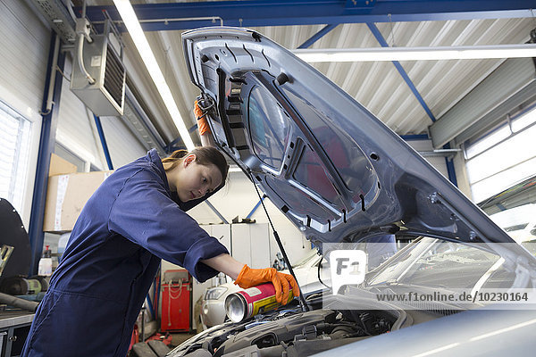Young woman working in repair garage  checking engine