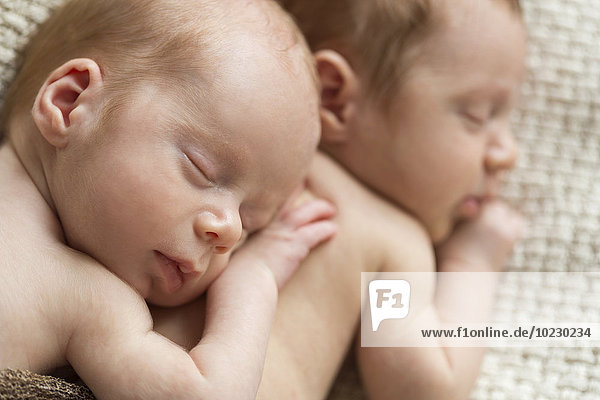 Neugeborene Zwillinge schlafen auf Decke