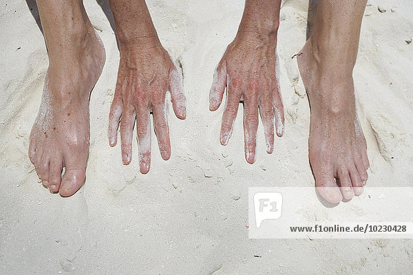 Woman's hands and feet in sand