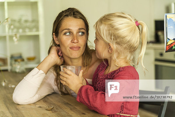 Mother looking at daughter holding glass