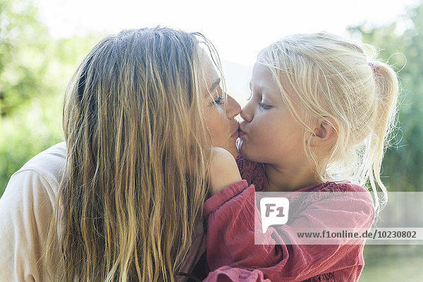 Mother and daughter kissing outdoors