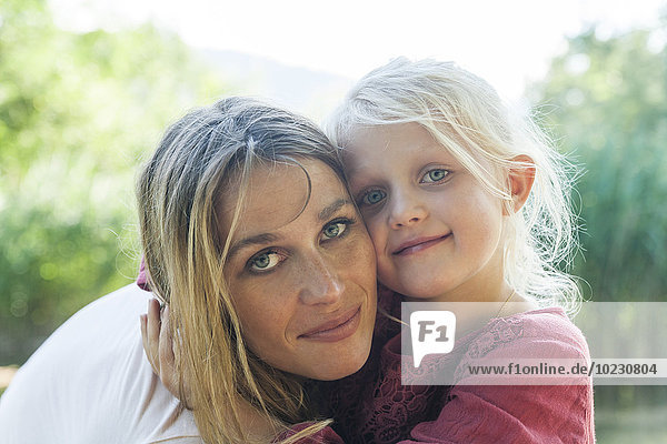 Portrait of smiling mother and daughter outdoors