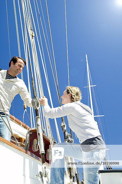 Mature man helping wife getting on a sailing ship